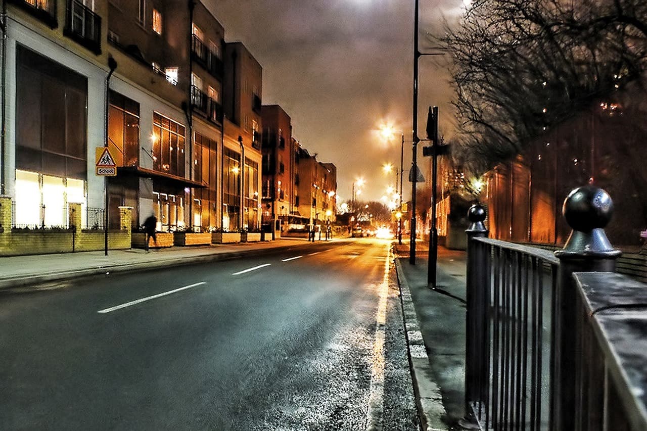 A London street at night, wet road and streetlights ahead